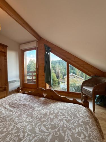 Le Chalet des Vanneaux في كسونبورت-لونجمير: غرفة نوم بسرير كبير ونافذة كبيرة