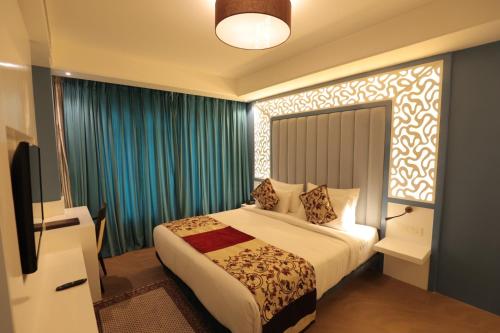 a hotel room with a bed and a television at Vilaasitaa Family Suites in Indore