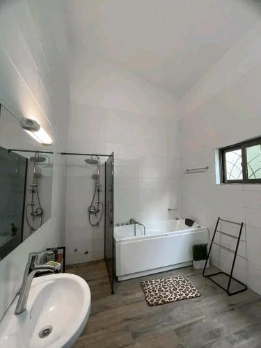 a white bathroom with a tub and a sink at Appartement de luxe avec piscine in Abomey-Calavi
