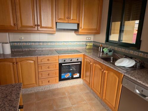 una cucina con mobili in legno, una stufa e un lavandino di Casa tres soles a Calasparra