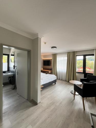 ein Hotelzimmer mit Bett und Wohnzimmer in der Unterkunft Hotel Paulushof in Rurberg
