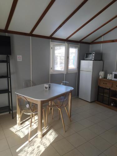 una cucina con tavolo, sedie e frigorifero di Camping Le Coulédous ad Aulus-les-Bains