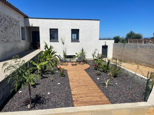 a garden in front of a house with a wooden walkway at Entre Campagne et Ville in Marcorignan