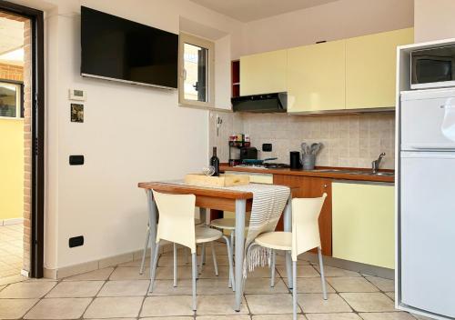 een keuken met een houten tafel en witte stoelen bij Holihome Vascello B21 in Tortoreto Lido