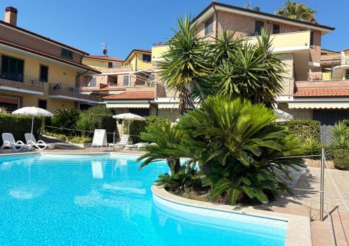 a swimming pool with palm trees in front of a building at Holihome Vascello B21 in Tortoreto Lido