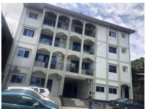 un edificio con auto parcheggiate di fronte di MADO Appartement a Bonamoussadi