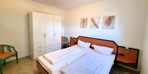 a bedroom with a bed and a cabinet at Boddenhof Apartment 50 - modern und freundlich, viel Sonne in Buschvitz