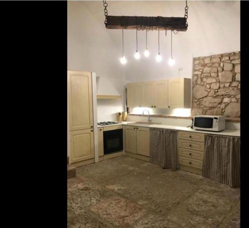 La Cantinetta في سان بيترو في كاريانو: مطبخ بدولاب بيضاء وجدار حجري