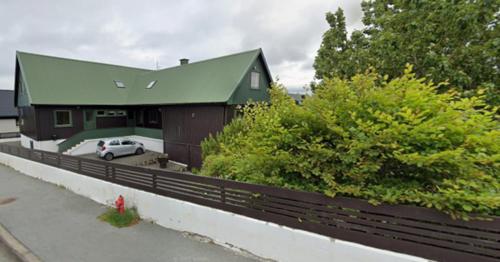 a house with a car parked in front of it at Guesthouse Leon in Tórshavn