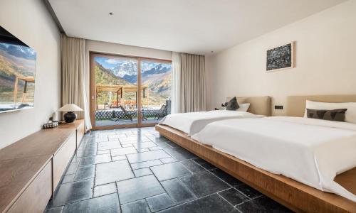 a bedroom with a large bed and a large window at Siguniang Mountain Waiting for the Wind Snow Mountain Guesthouse in Mount Siguniang