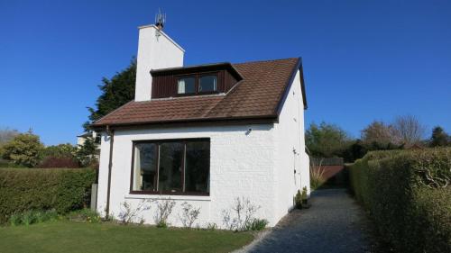 a small white house with a brown roof at An Cala in Connel