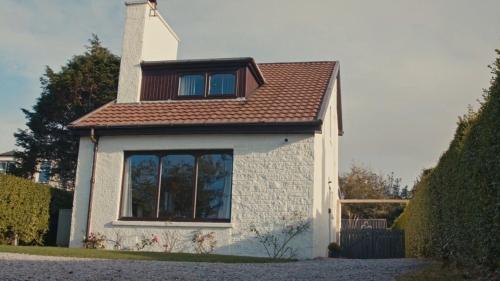 a small white house with a brown roof at An Cala in Connel
