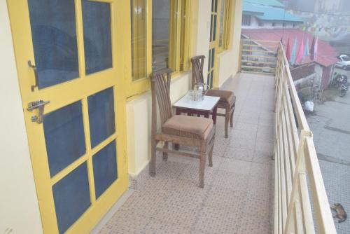 een veranda met 2 stoelen en een tafel op een balkon bij Sahil cottage in Chamba