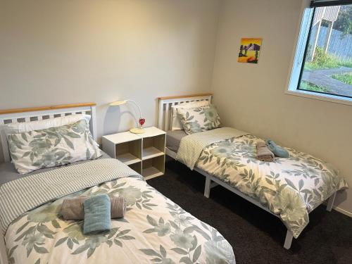 Albany Sunny Deck Retreat في أوكلاند: غرفة نوم بسريرين ومصباح ونافذة