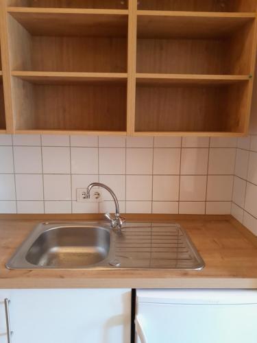 encimera de cocina con fregadero y armarios de madera en Mein Wein Apartment, en Krems an der Donau