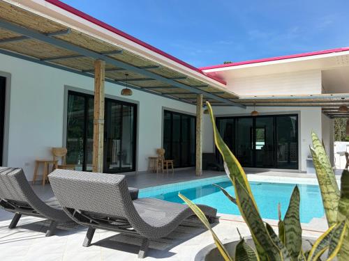 a patio with two chairs and a swimming pool at Pinky Bungalow Resort & Villa - SHA Extra Plus in Ko Lanta