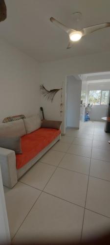 a living room with a couch and a ceiling fan at Apartamento pé na areia no centro de Bertioga in Bertioga