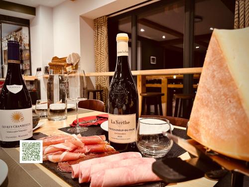 een tafel met twee flessen wijn en wat vlees bij La Grange des Eulets in Bourg-Saint-Maurice
