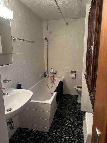 a bathroom with a tub and a sink and a toilet at Faido Apartment in Faido