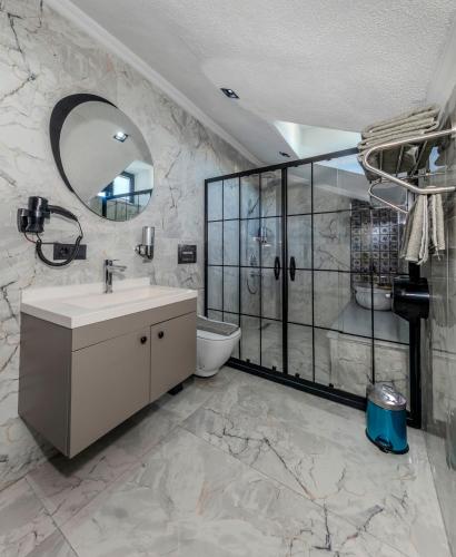 a bathroom with a sink and a shower and a toilet at AirGate Airport Hotel in Arnavutköy
