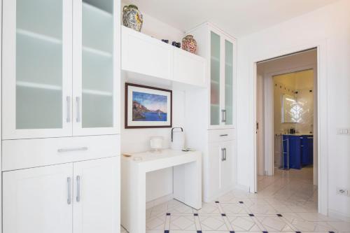 a white kitchen with a sink and white cabinets at Villa Elisa by My Villa Collection in Conca dei Marini