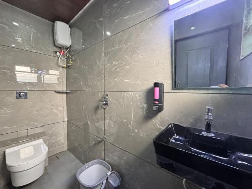 ein Badezimmer mit Waschbecken, Toilette und Spiegel in der Unterkunft Indraprastha Cottage in Alibag