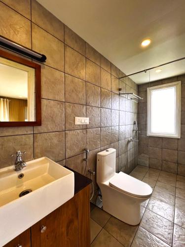 a bathroom with a white toilet and a sink at Hornbill Resorts in Suryanelli