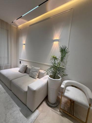 een woonkamer met een witte bank en een plant bij Altair in Simkent