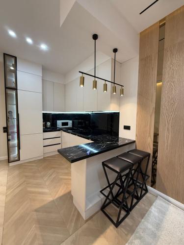 een keuken met zwarte aanrechtbladen en witte kasten bij Altair in Simkent