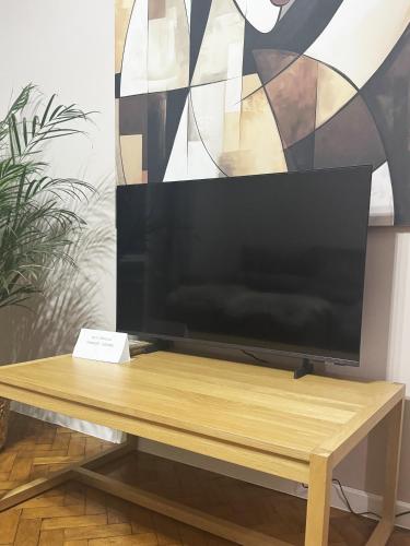una TV a schermo piatto appoggiata su un tavolo di legno di Ultra Central Nice Ap a Chişinău