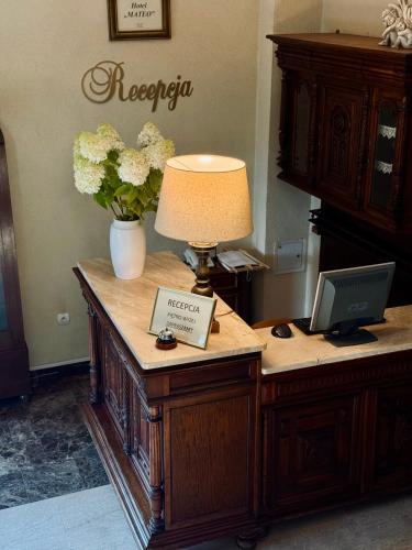 a desk with a lamp and flowers on top of it at Hotel Mateo in Stopnica
