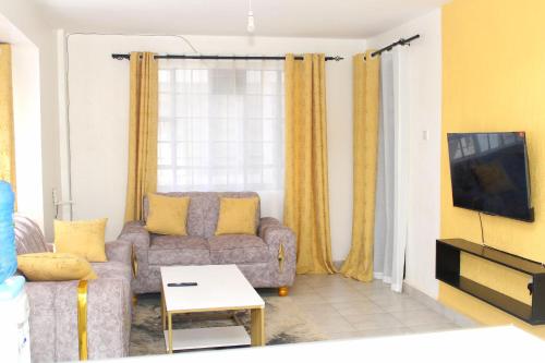 een woonkamer met een bank en een tv bij Willary Heights Apartment in Bungoma