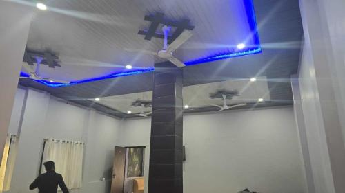 Una persona caminando en una habitación con un techo con luces azules. en Hotel O Shree Paying Guest House, en Rāmnagar