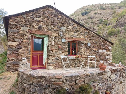 una pequeña casa de piedra con mesa y sillas al aire libre en Ecogite du Mas de Trape, en Talau
