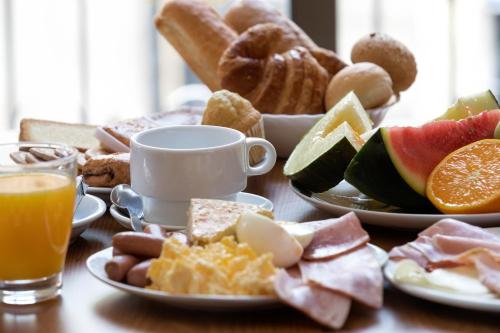 Una mesa cubierta con platos de desayuno y jugo de naranja. en Cuatro Naciones, en Barcelona