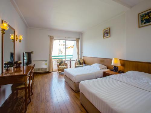 um quarto de hotel com duas camas e uma secretária e uma televisão em Sirin Hotel Hua Hin em Hua Hin