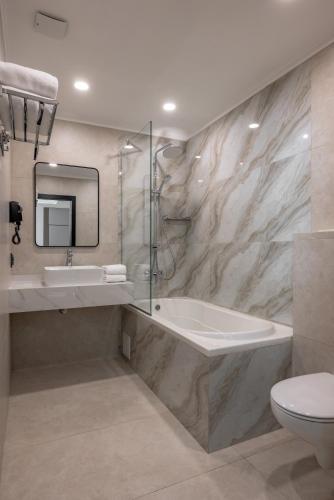 a bathroom with a tub and a sink and a toilet at Mountain View Residence Hotel in Almaty