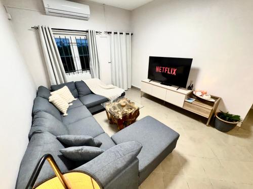 ein Wohnzimmer mit einer blauen Couch und einem Fernseher in der Unterkunft Zephyr House 3BR Pool, Rooftop & Ocean View in Grand-Gaube