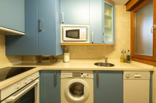 a kitchen with a washing machine and a microwave at Apartamento Mirador Playa de Barro in Barro de Llanes