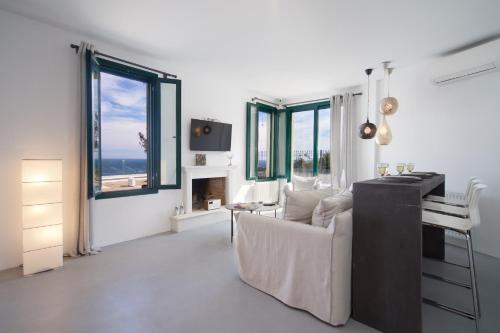 een woonkamer met een bank, een bureau en ramen bij Villa Ilenia in Skála Kefalonias