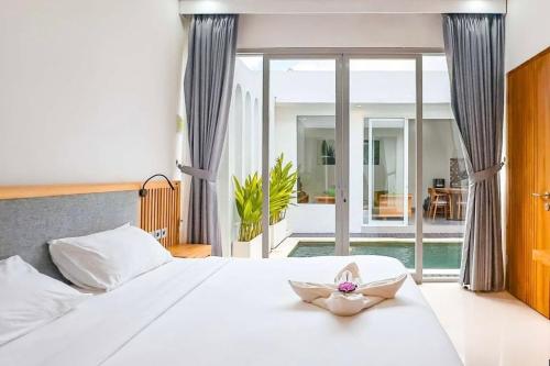 a bedroom with a white bed with a flower on it at Luxurious Semeniyak new 2BR villa with a pool in Seminyak