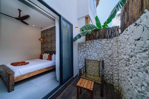 una camera da letto con un letto e un muro di pietra di Ô TALIA Hôtel and SPA a Nungwi