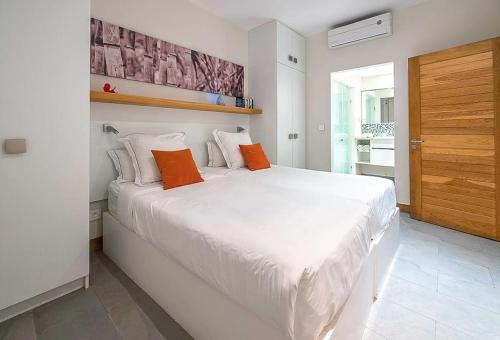 Cape Bay by AAA Rentals - Cap Malheureux في كاب مالهيريوكْسْ: غرفة نوم بسرير أبيض كبير مع وسائد برتقالية