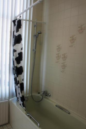 a bathroom with a shower with a cow shower curtain at New City Hotel Scheveningen in Scheveningen