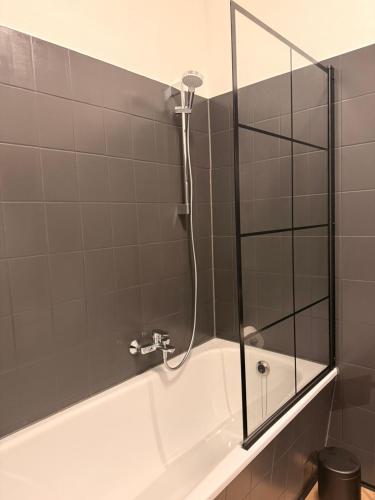 a white bath tub with a glass shower door at StaySimplyHaven - Modernes City-Apartment, King-Size Bett, 55'' Smart-TV, Self Check-In in Braunschweig