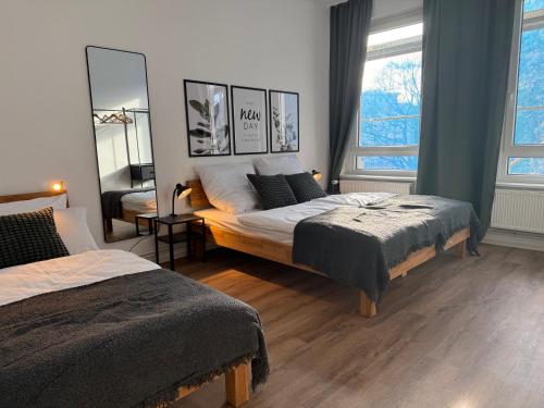 a bedroom with two beds and a mirror at StaySimplyHaven - Modernes City-Apartment, King-Size Bett, 55'' Smart-TV, Self Check-In in Braunschweig