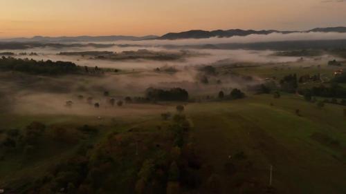 una vista aerea di un campo con nebbia nella valle di Mystic Twistic a Vîrfurile