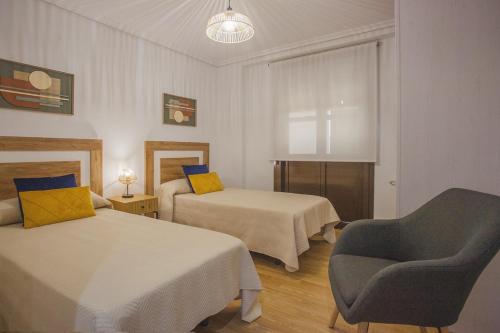 a hotel room with two beds and a chair at Castillo Buenavista in Ponferrada