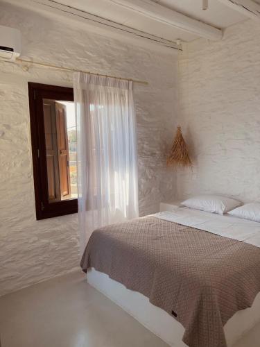 a white bedroom with a bed and a window at Conte Kea in Koundouros