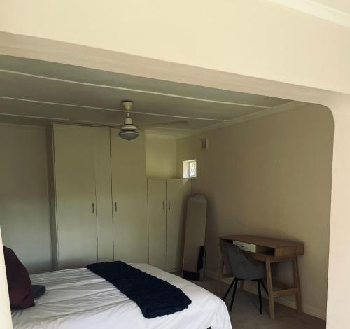 a bedroom with a bed and a table and a desk at LaPoch Guesthouse in Durban